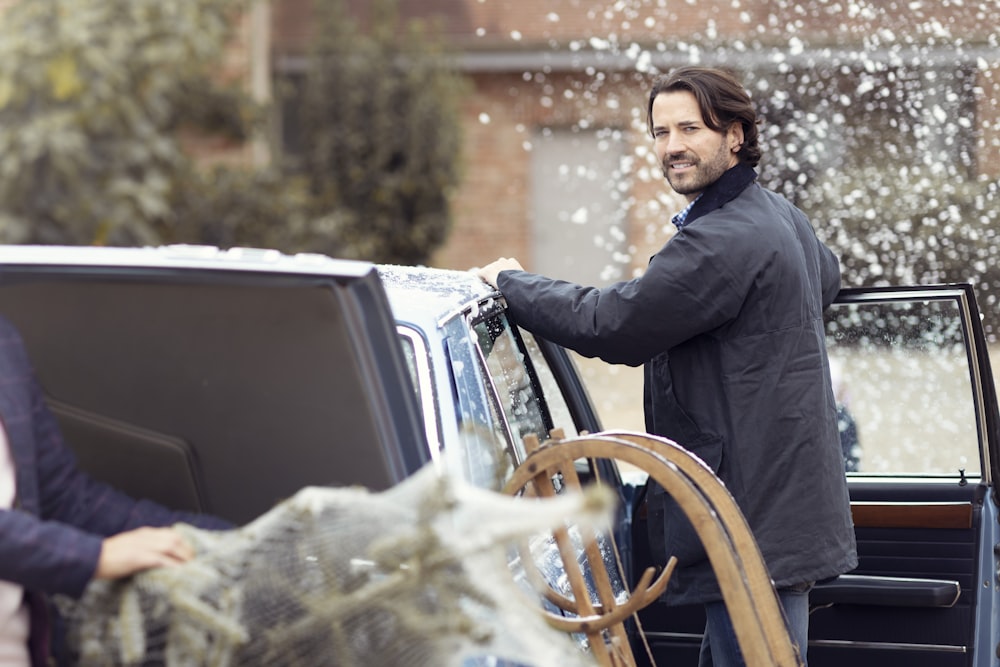 a man standing next to a parked car