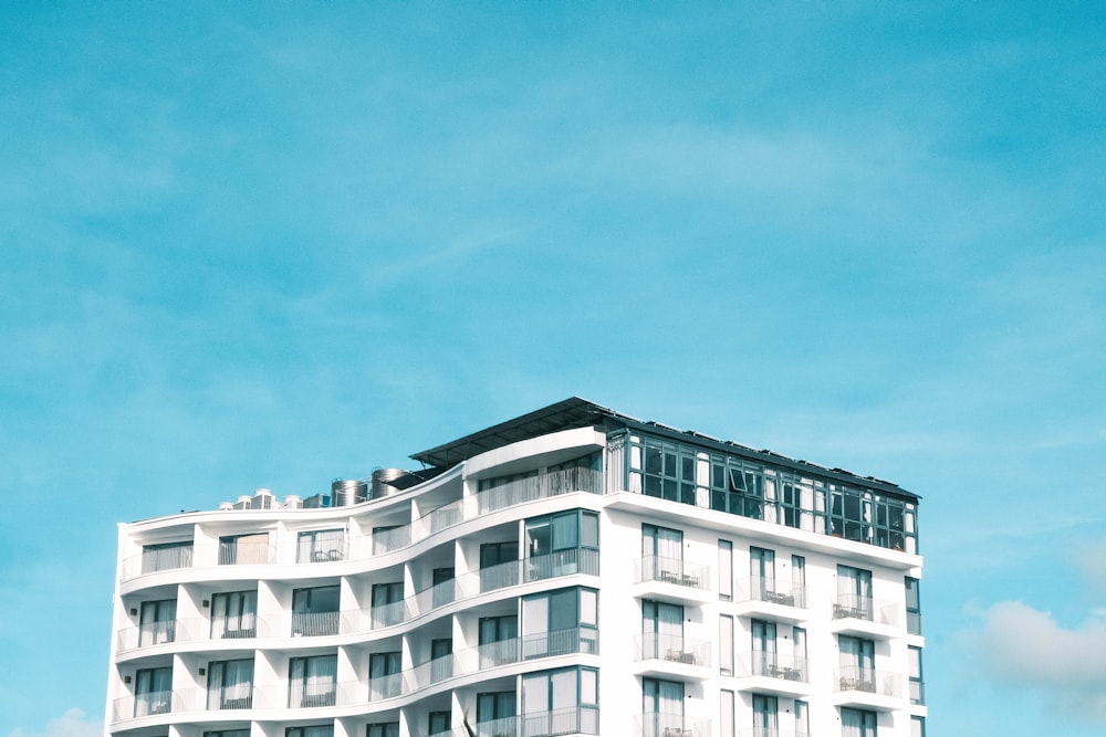 a tall white building with balconies on top of it