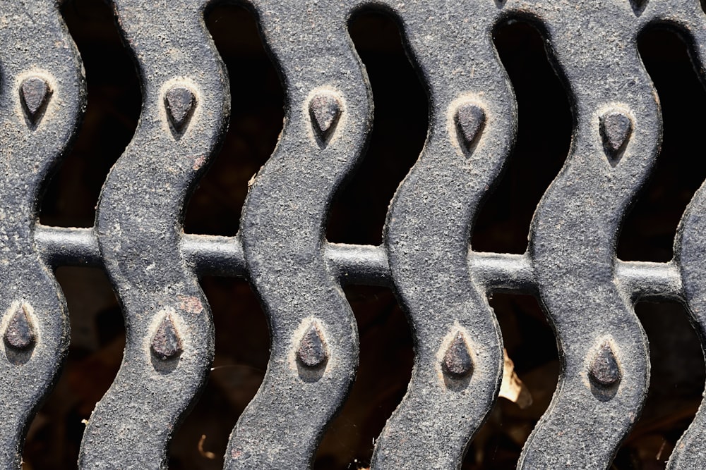 a close up of a metal grate with drops of water on it