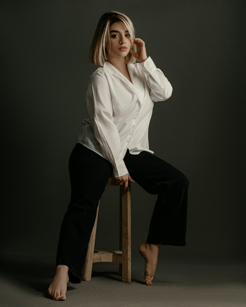 a woman sitting on a stool posing for a picture
