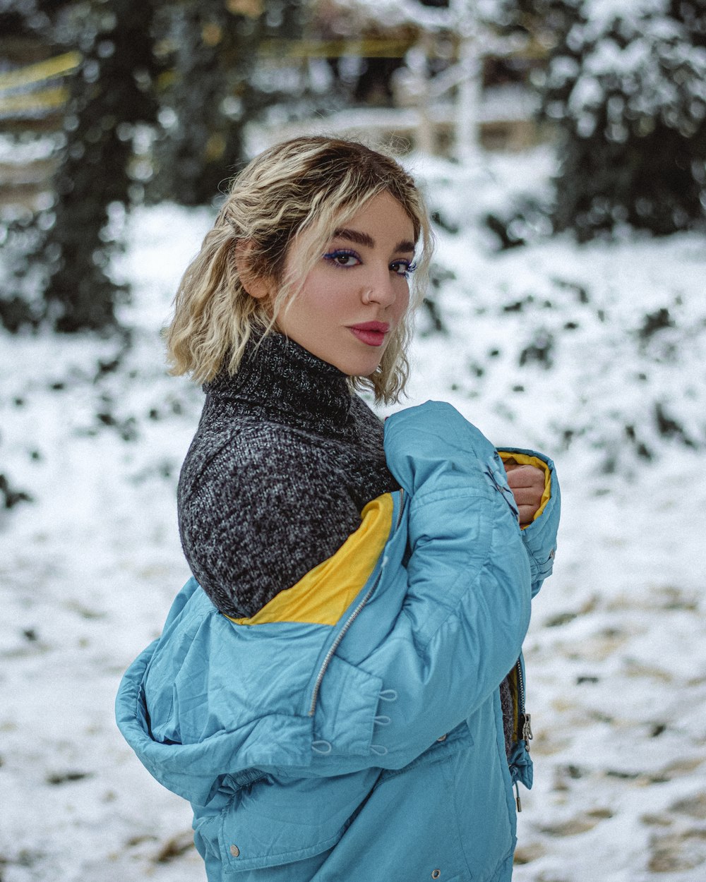 a woman standing in the snow wearing a blue jacket