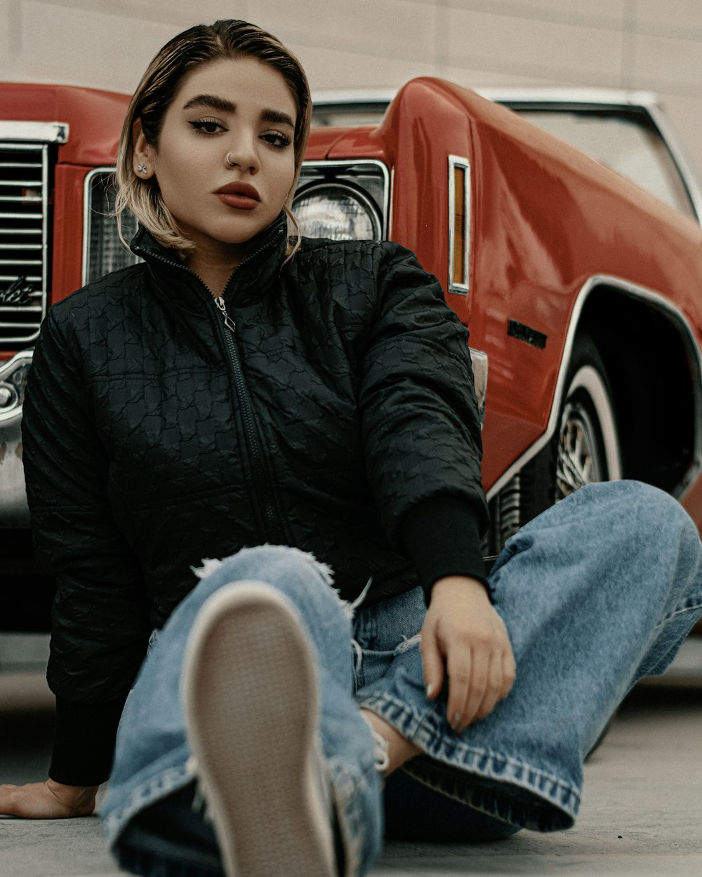 a woman sitting on the ground next to a red truck