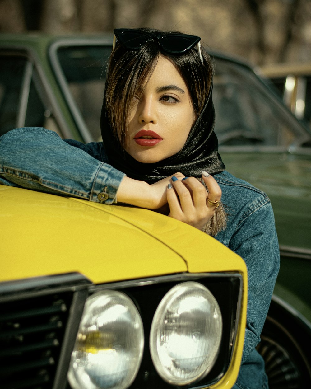 a woman leaning on the hood of a yellow car