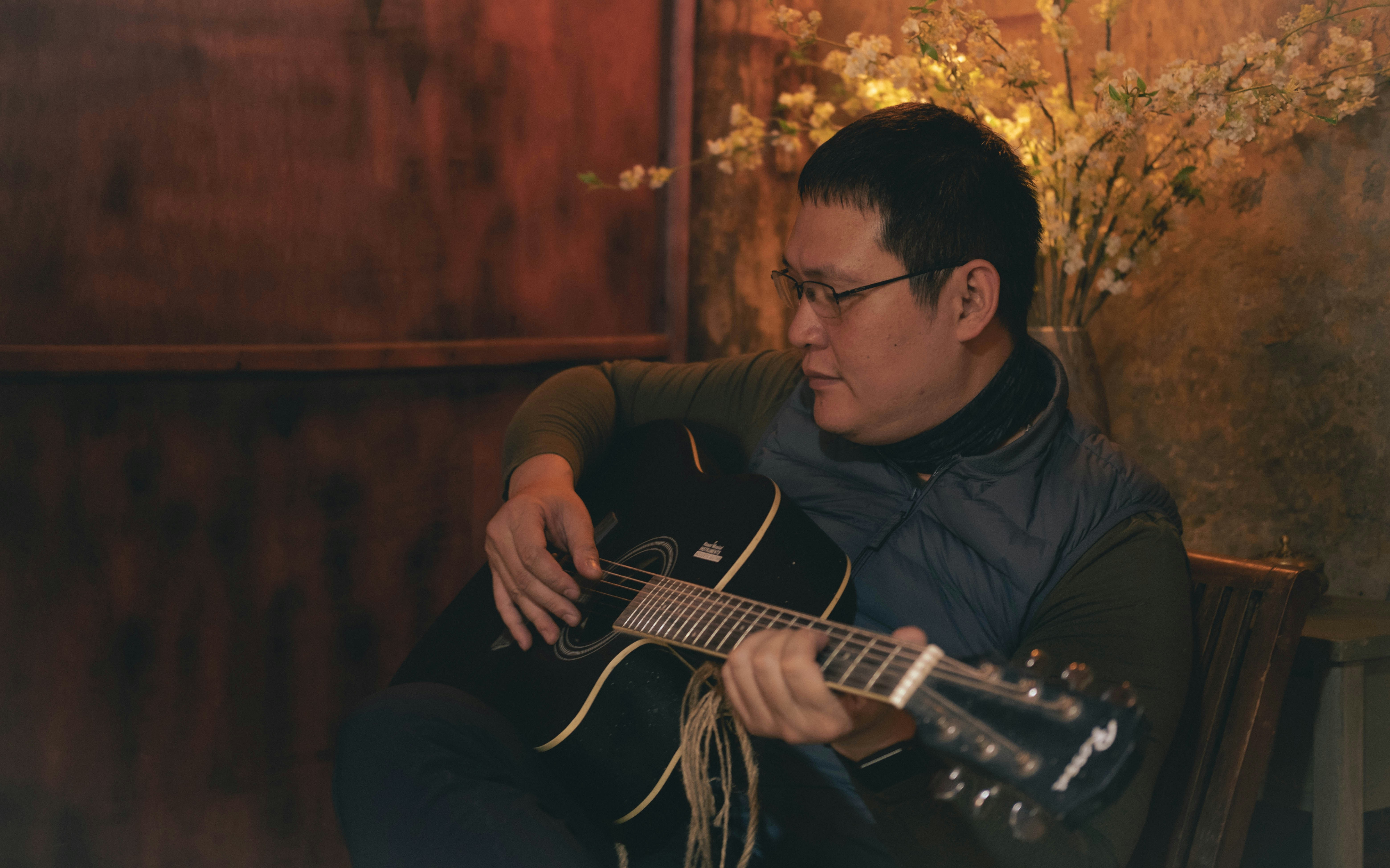 a man sitting in a chair playing a guitar