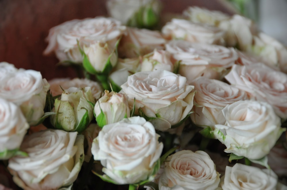 a bunch of white roses in a wooden bowl