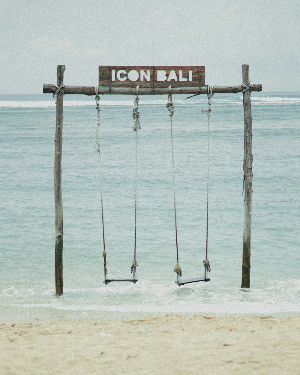 a wooden sign hanging from the side of a beach