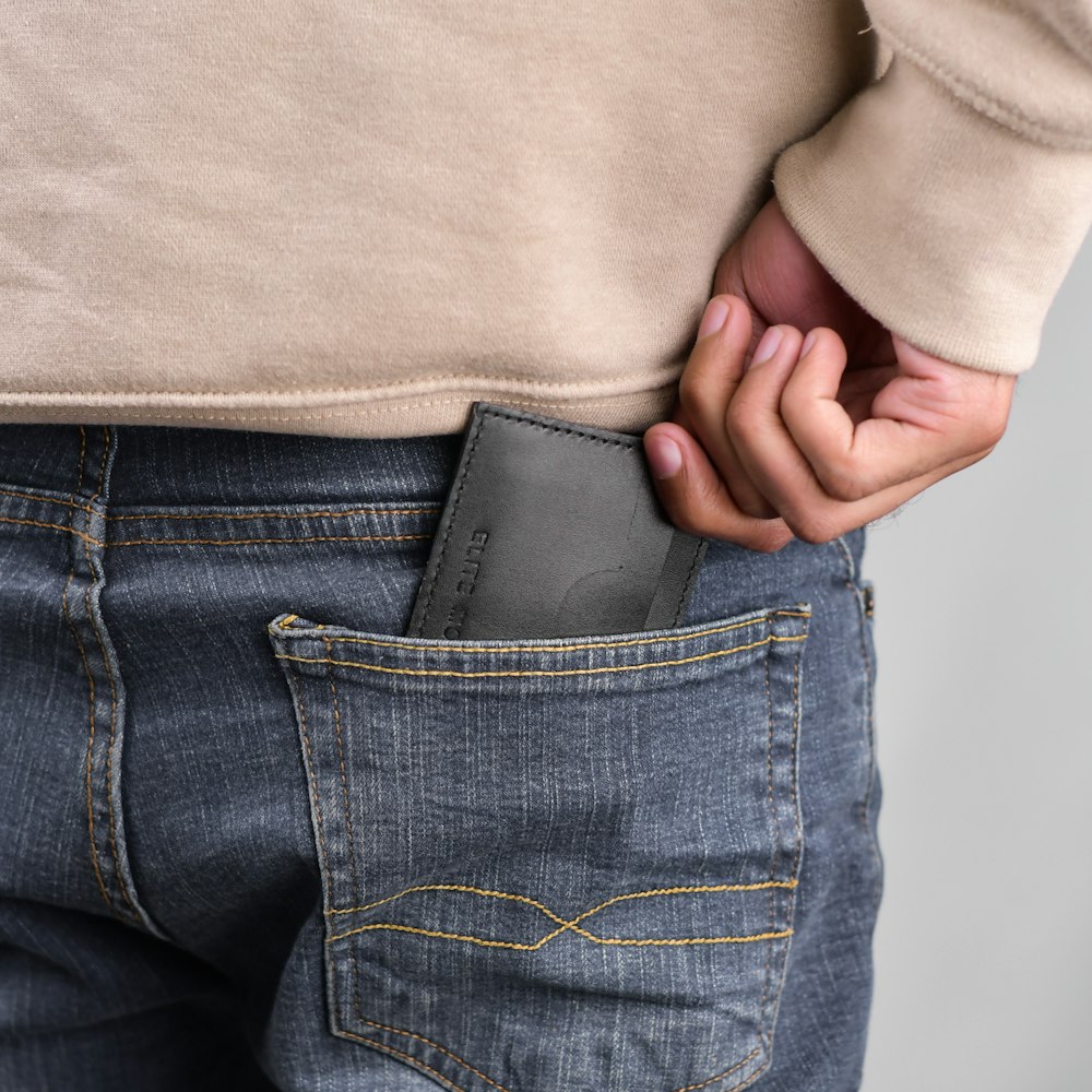 a person holding a cell phone in their pocket