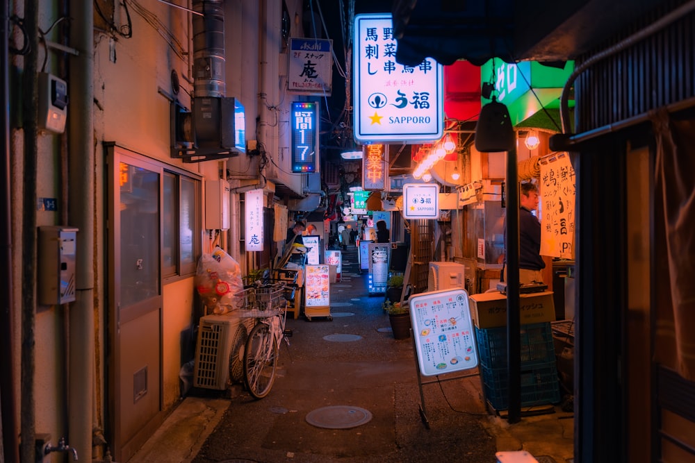 a narrow alley way with signs and a bicycle parked on the side