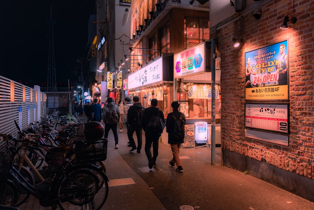 a group of people walking down a street at night