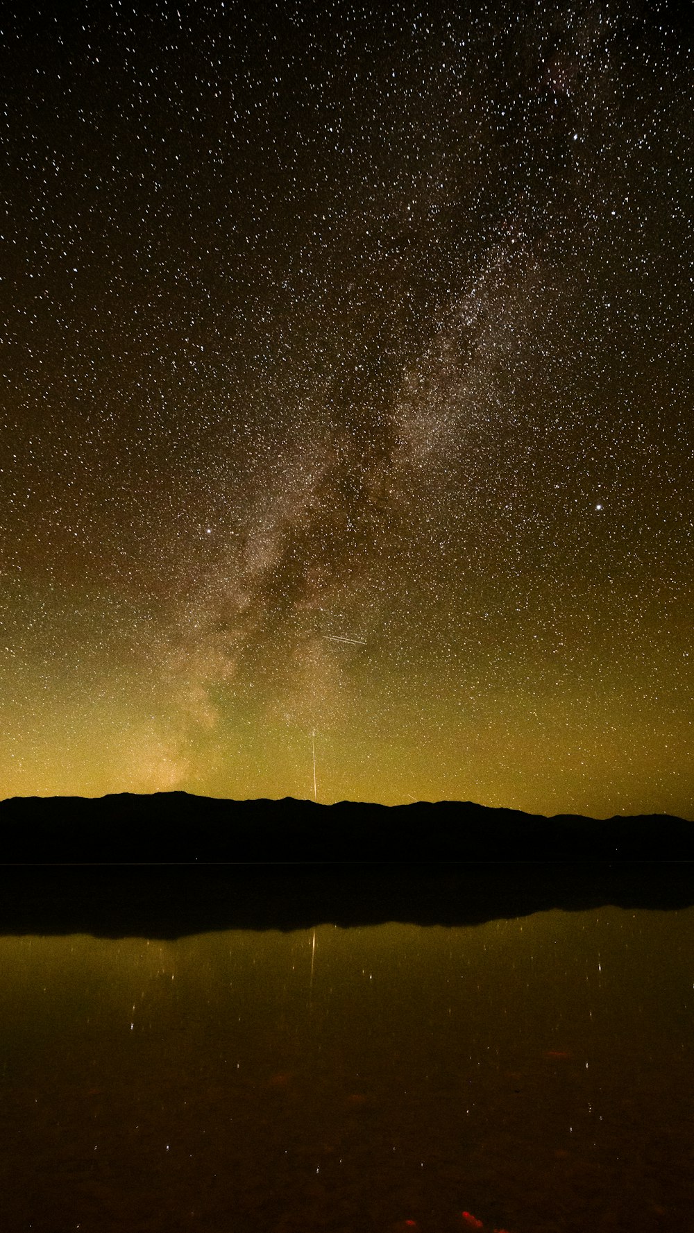 the night sky is filled with stars above a body of water