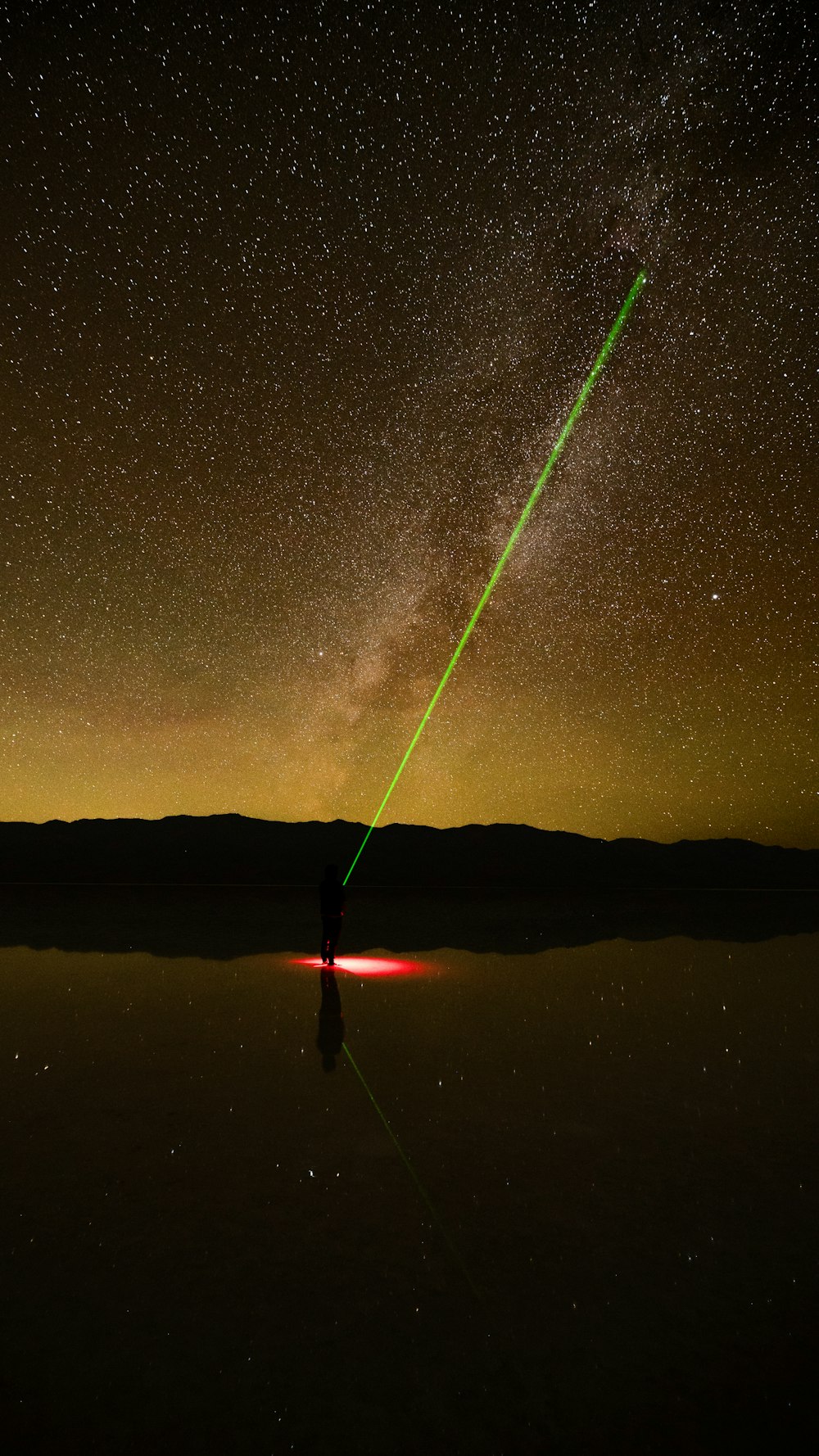 a green laser is visible in the night sky