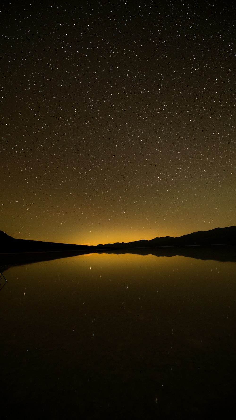 Un lago por la noche con estrellas en el cielo