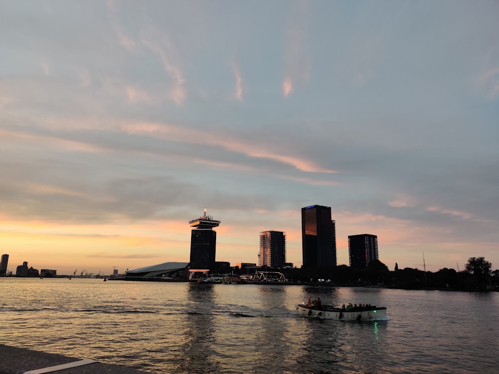 a boat traveling down a river next to tall buildings