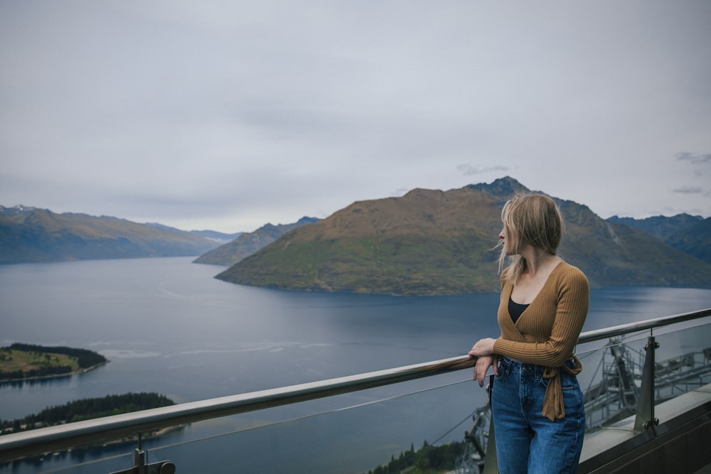 a woman standing on a balcony overlooking a body of water