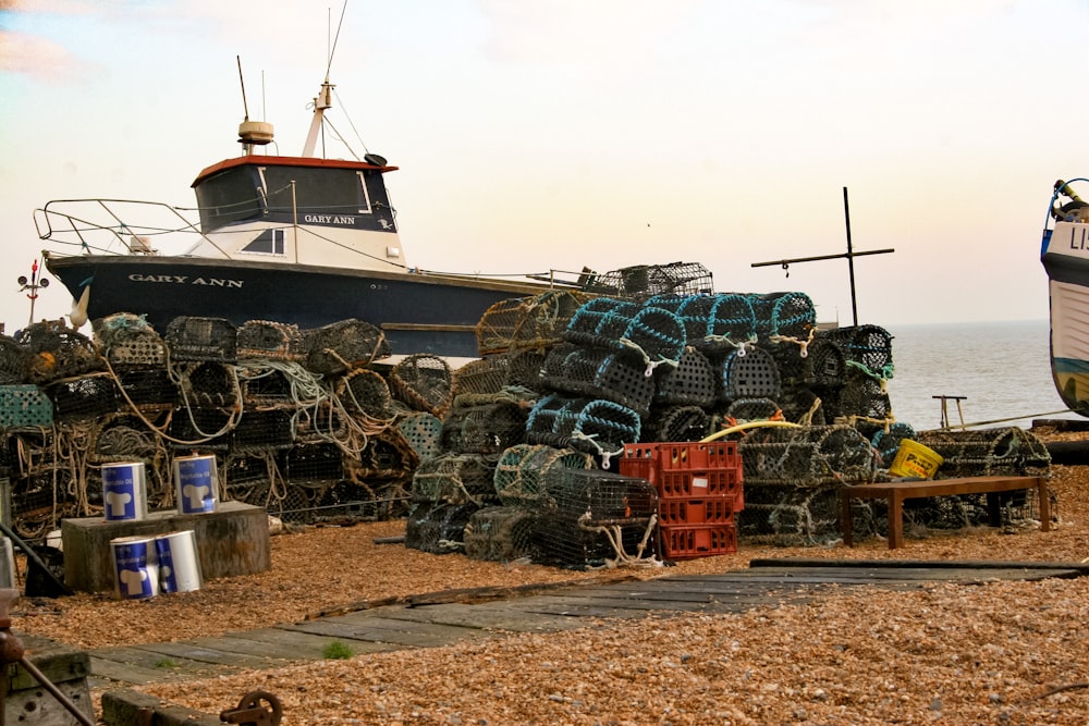 a boat sitting on top of a beach next to a pile of lobster traps