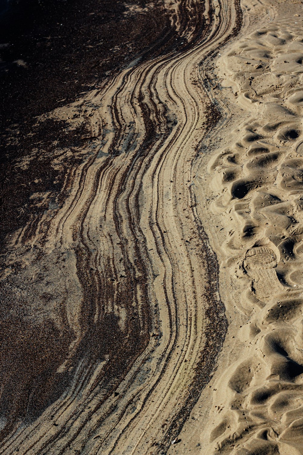 a view of a sandy beach with tracks in the sand