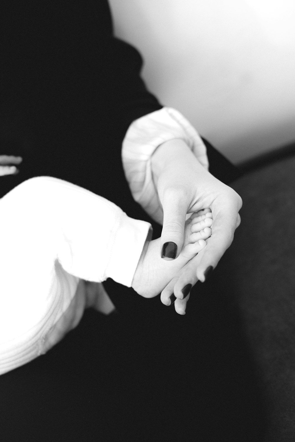 a black and white photo of a woman holding a baby's hand