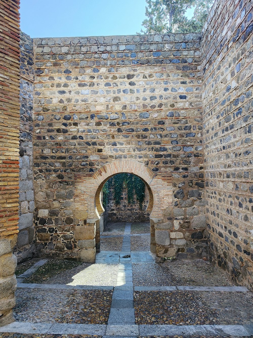 돌 산책로가 있는 벽돌 건물의 돌 아치형 통로