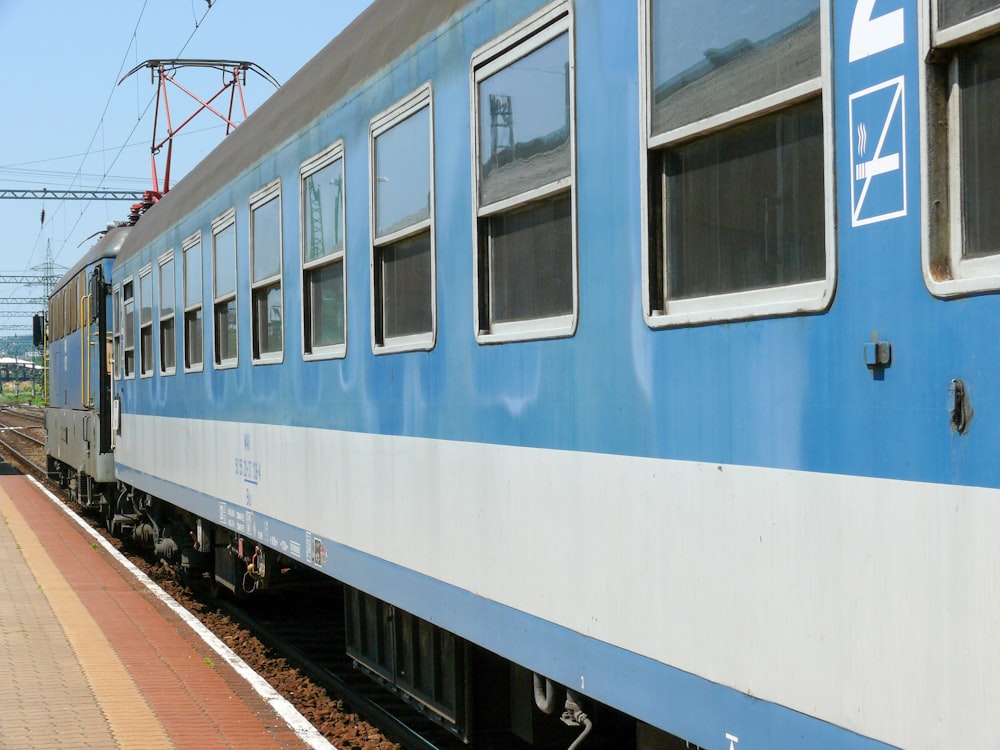um trem azul e branco viajando pelos trilhos do trem