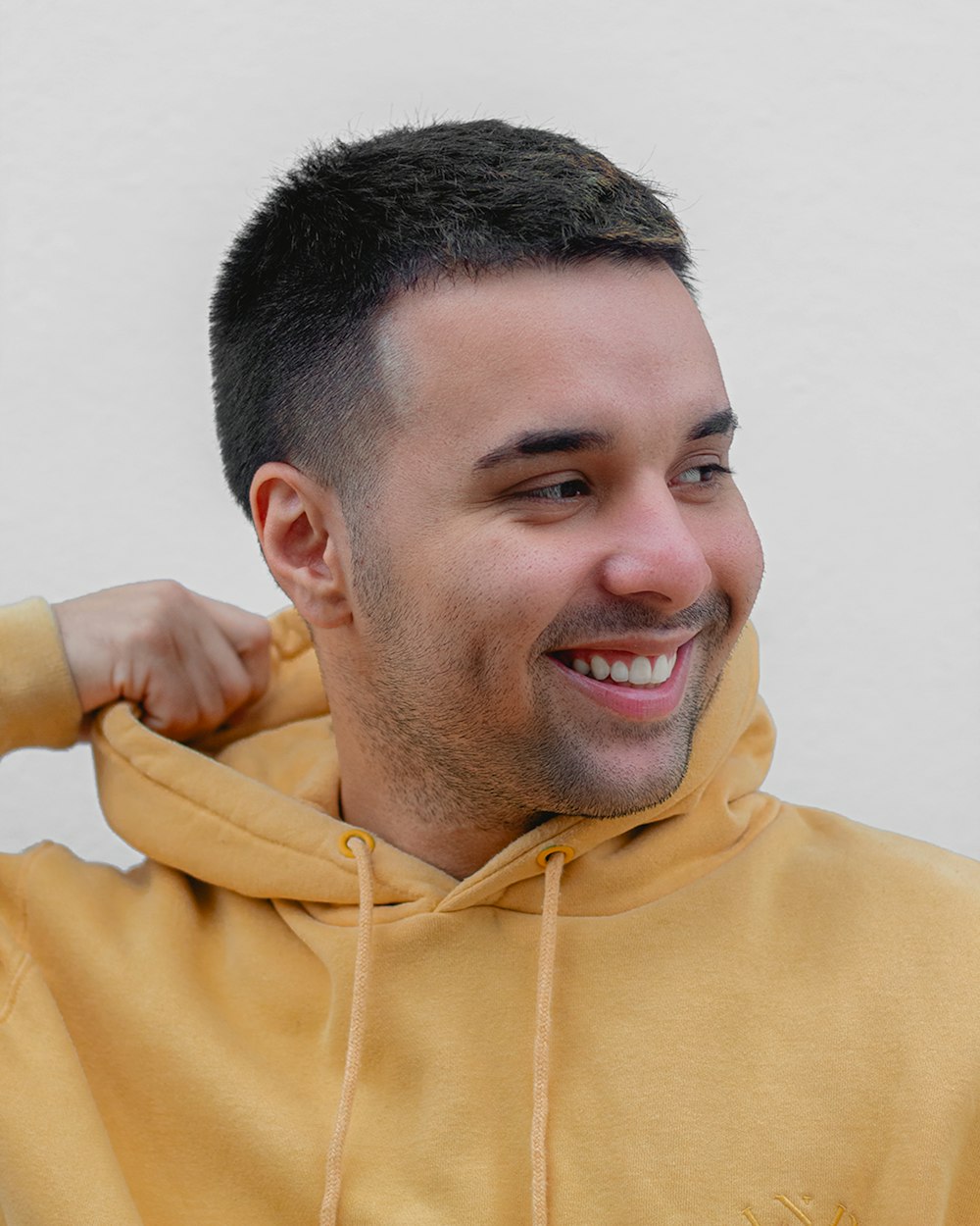 a man in a yellow hoodie smiling at the camera