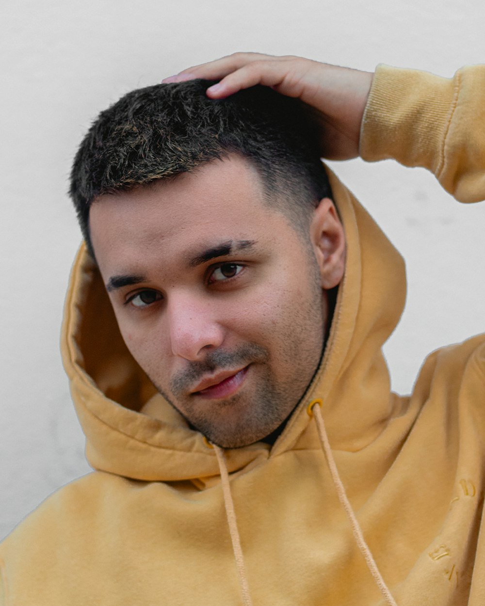 a man in a yellow hoodie holding his hair