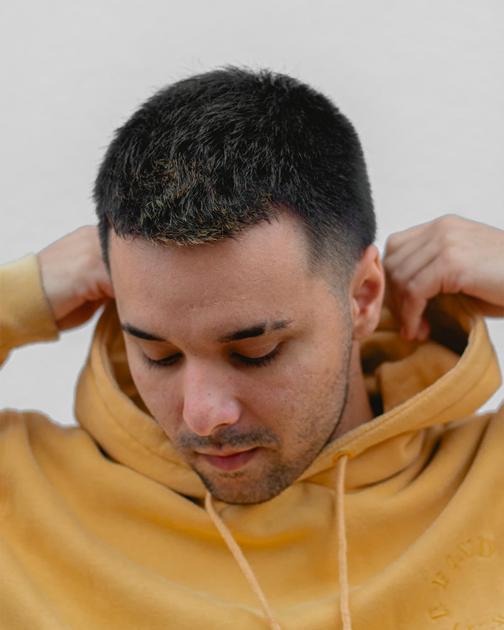 a man in a yellow hoodie holding his hands on his head