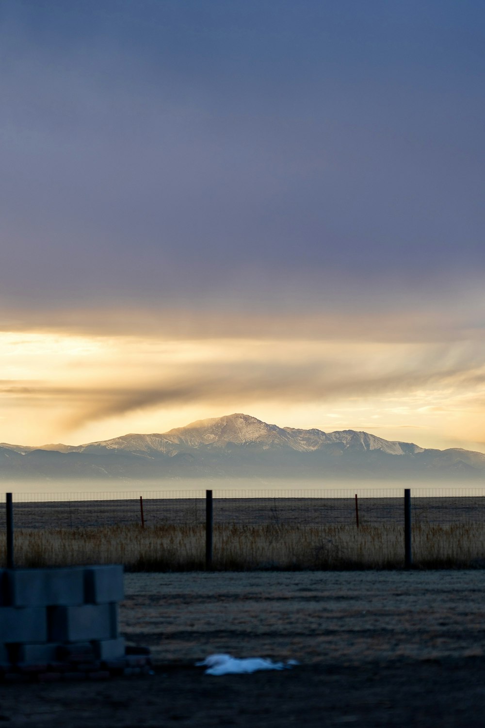 a field with a fence and mountains in the distance