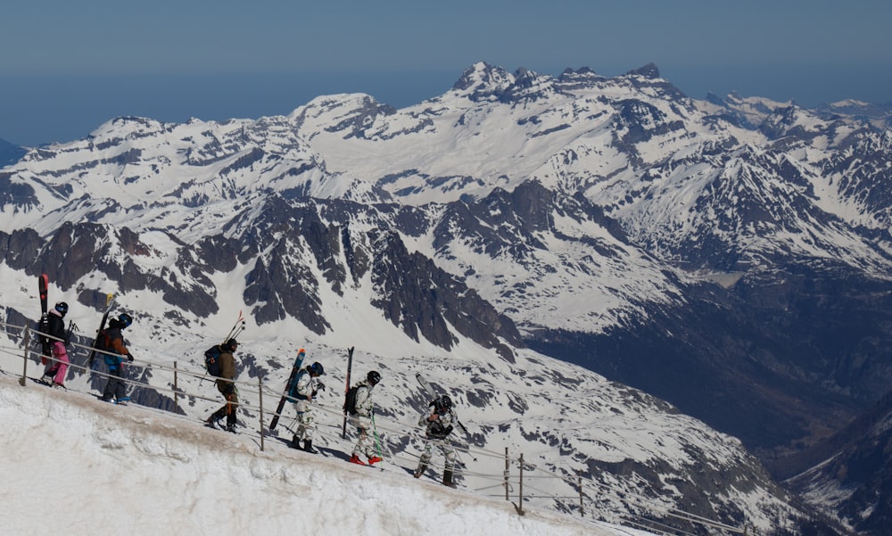 a group of people walking up the side of a snow covered mountain