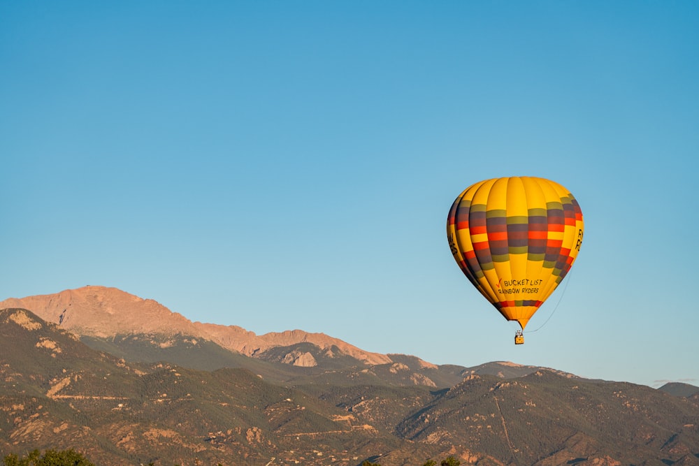 a hot air balloon flying over a mountain range