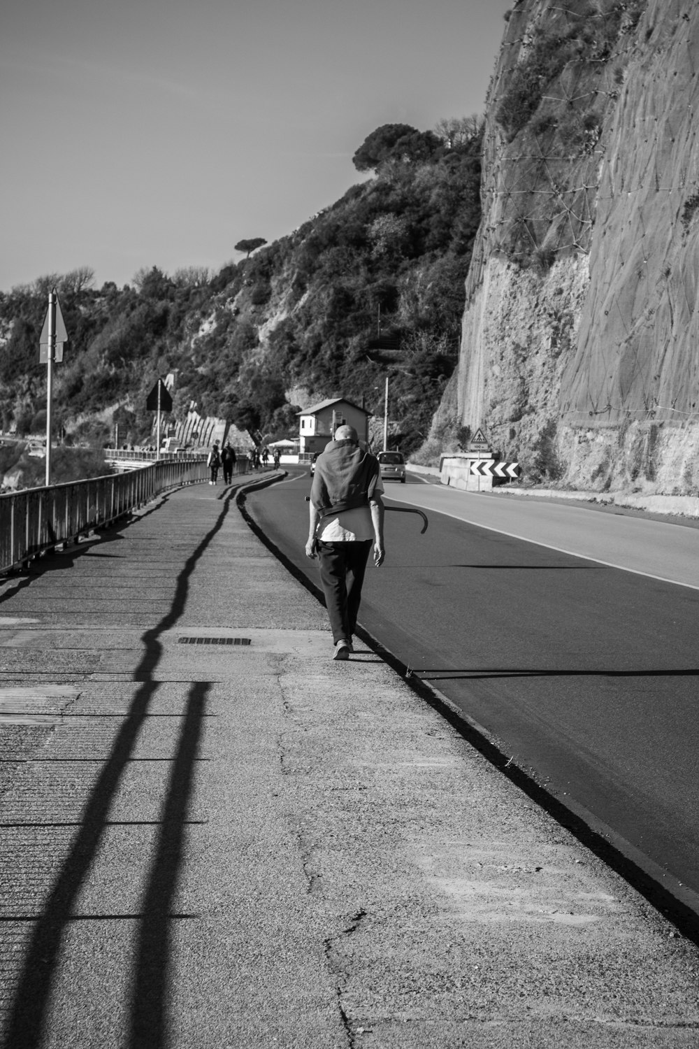 a black and white photo of a person walking down a road