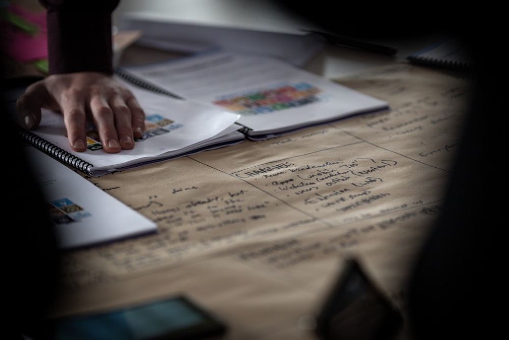 a person writing on a notebook with a pen