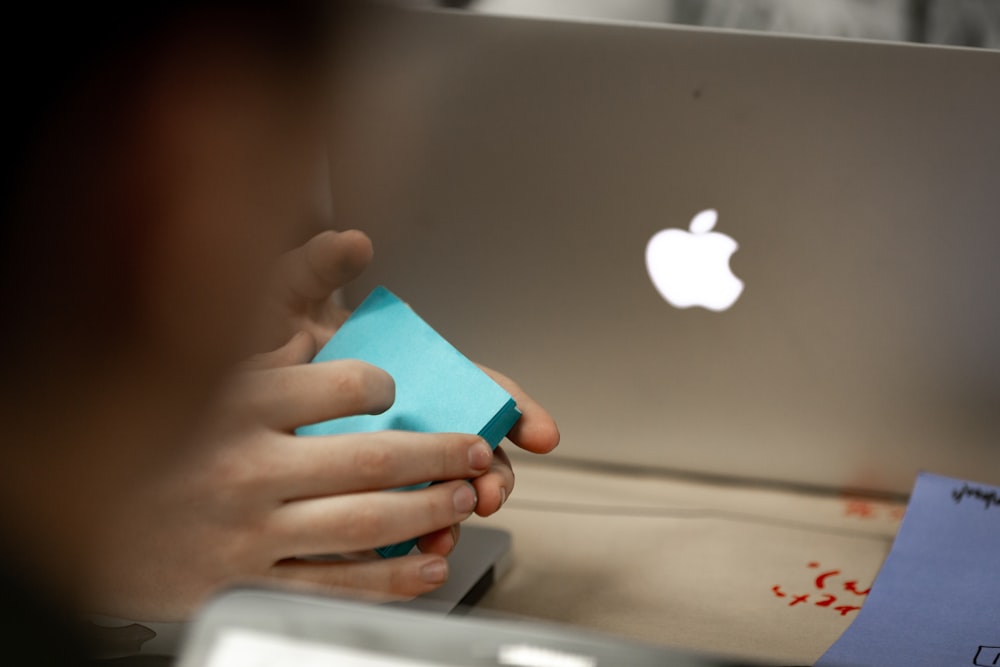 a person holding a piece of paper in front of a laptop