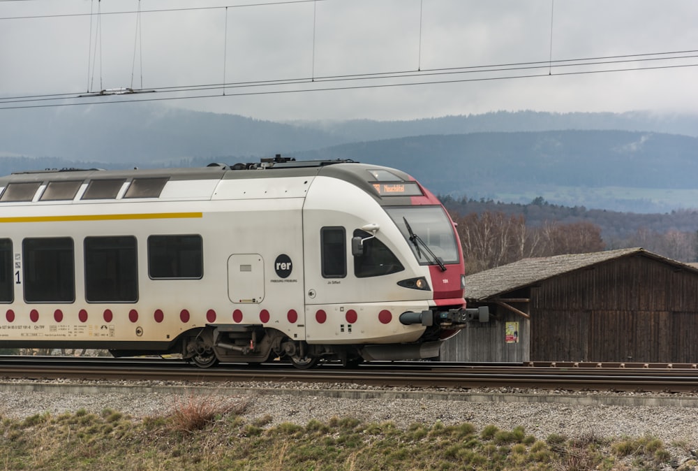 a white train traveling down train tracks next to a forest