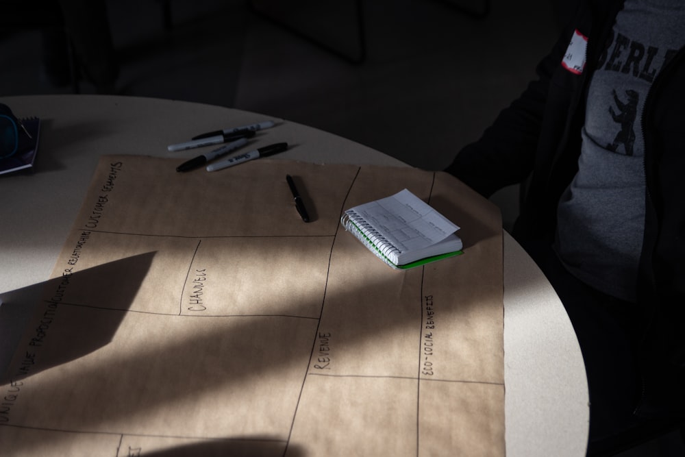 una persona sentada en una mesa con un cuaderno y un bolígrafo