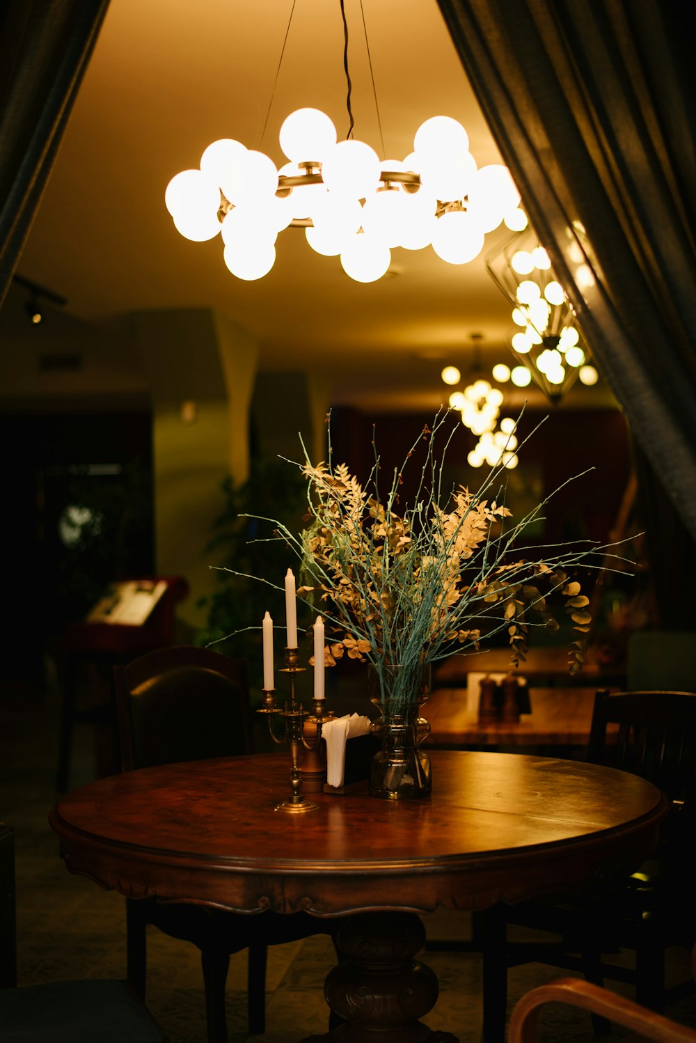 a table with a vase of flowers and candles on it