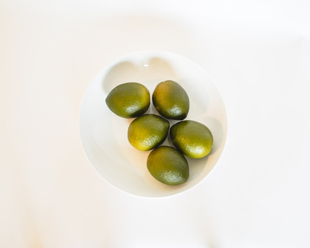 a white bowl filled with limes on top of a table