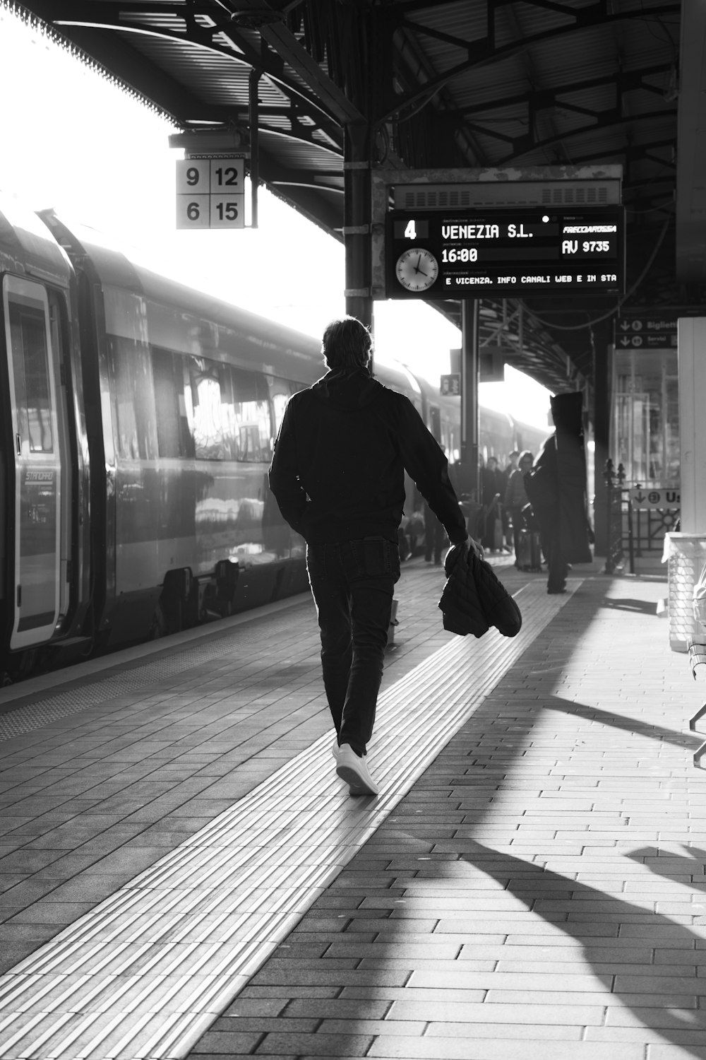 a man walking down a train platform next to a train