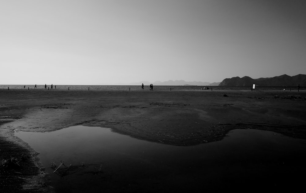 a group of people standing on a beach next to a body of water