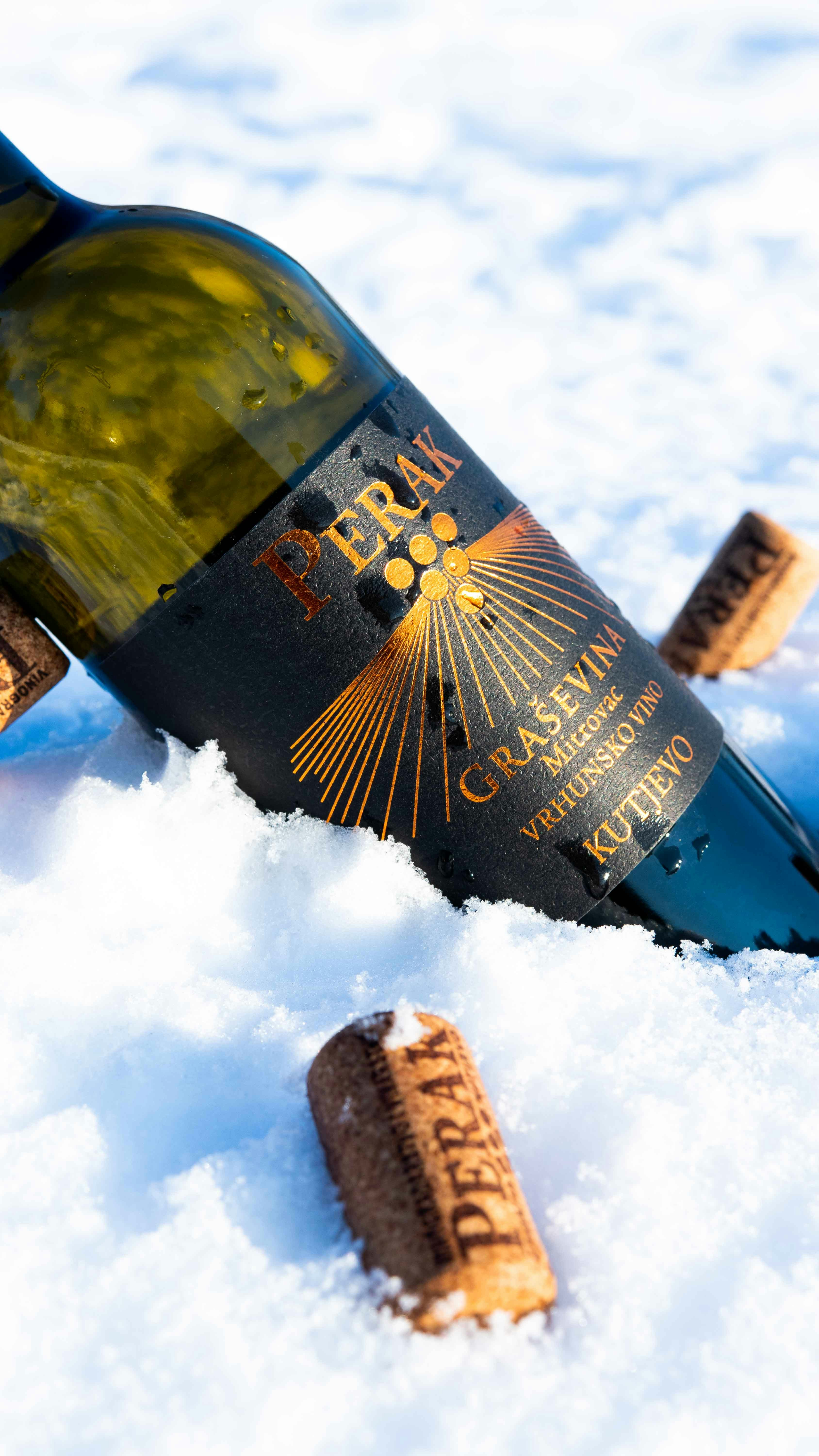 a bottle of wine sitting on top of a pile of snow