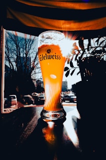 a glass of beer sitting on top of a wooden table