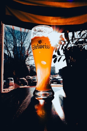 a glass of beer sitting on top of a wooden table