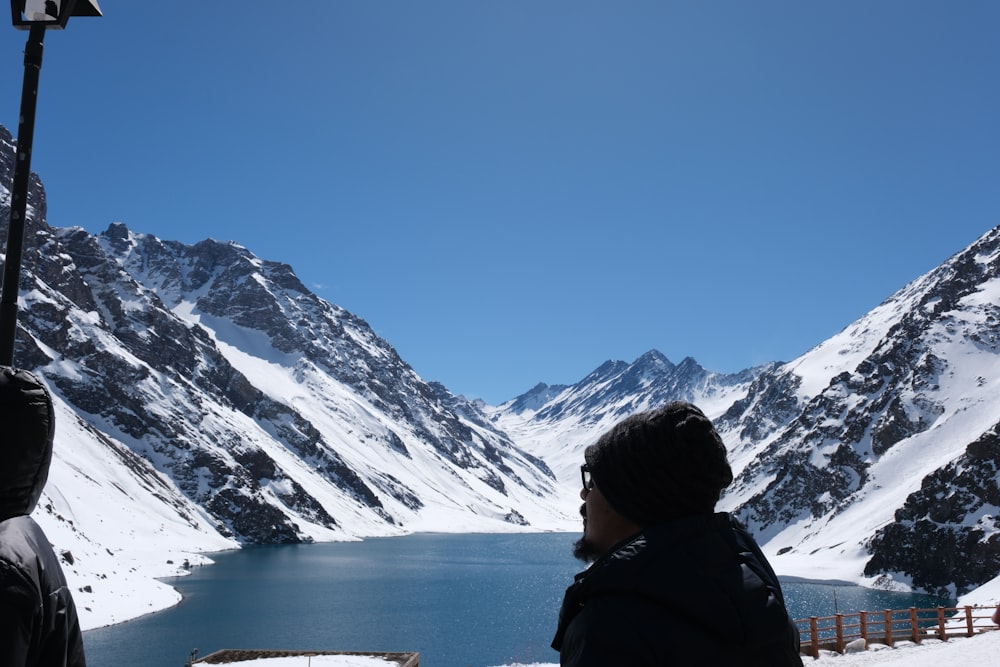 una persona in piedi davanti a un lago di montagna