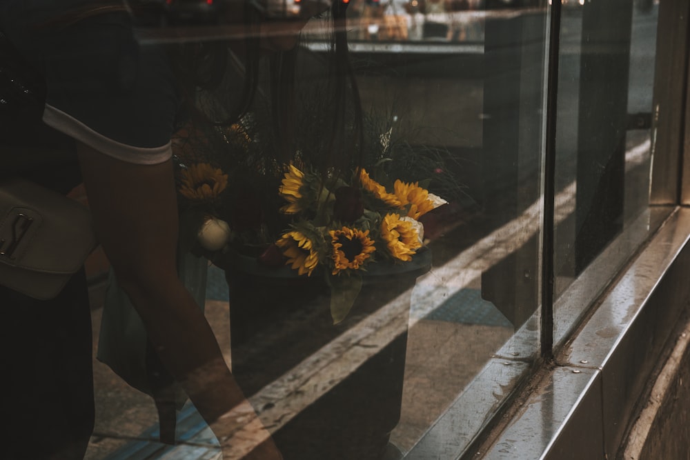a person standing next to a window with sunflowers in it