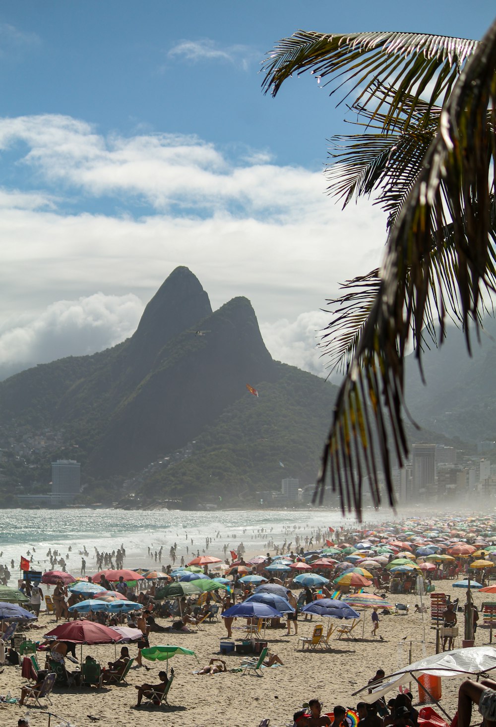 a crowded beach with a mountain in the background