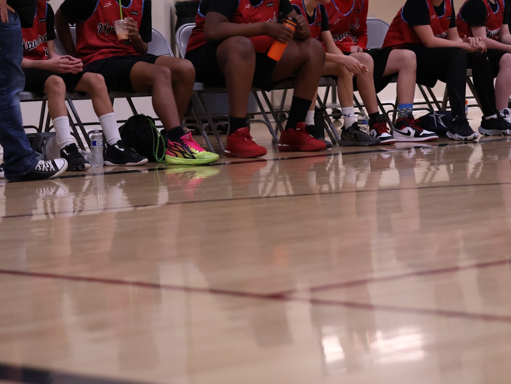 a group of young people sitting on top of a basketball court