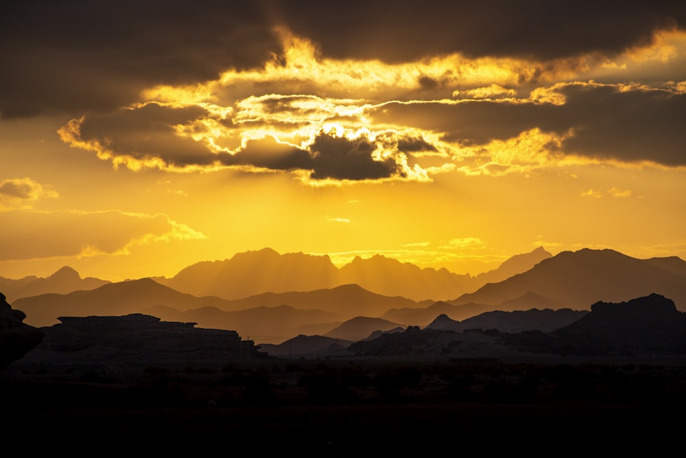 the sun is shining through the clouds over the mountains