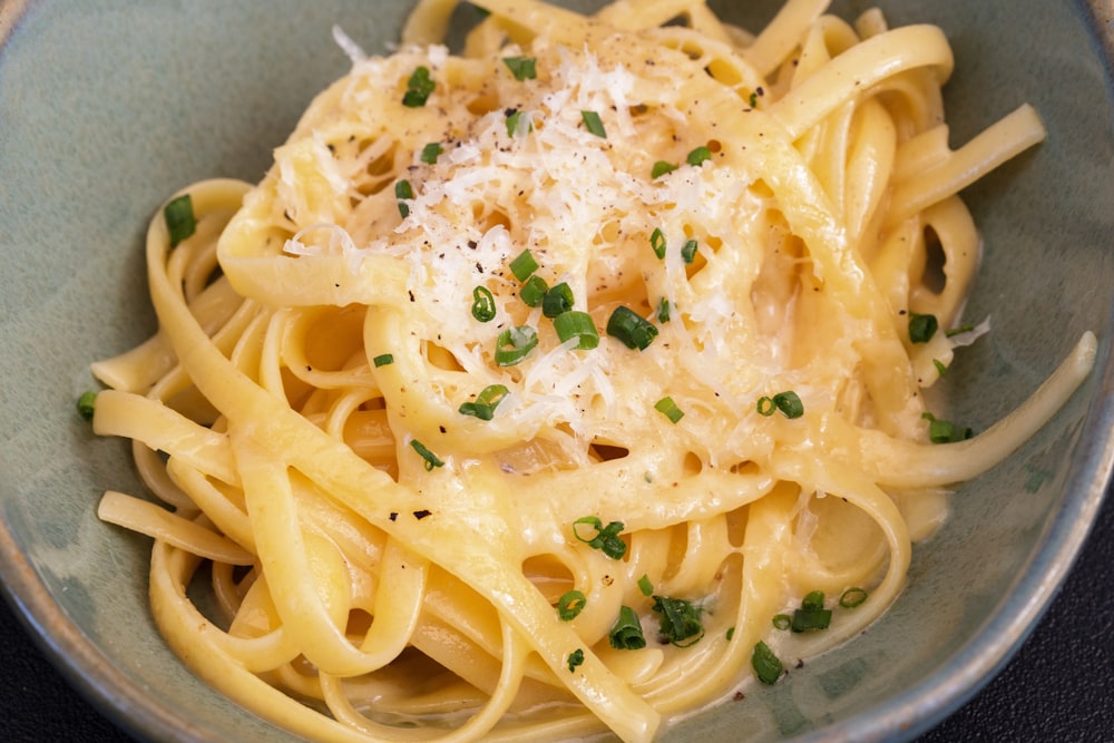 a bowl of pasta with parmesan cheese and chives