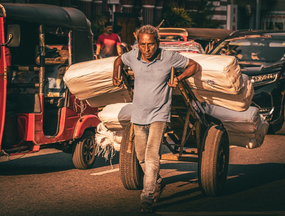 a man pushing a cart with bags on it down a street