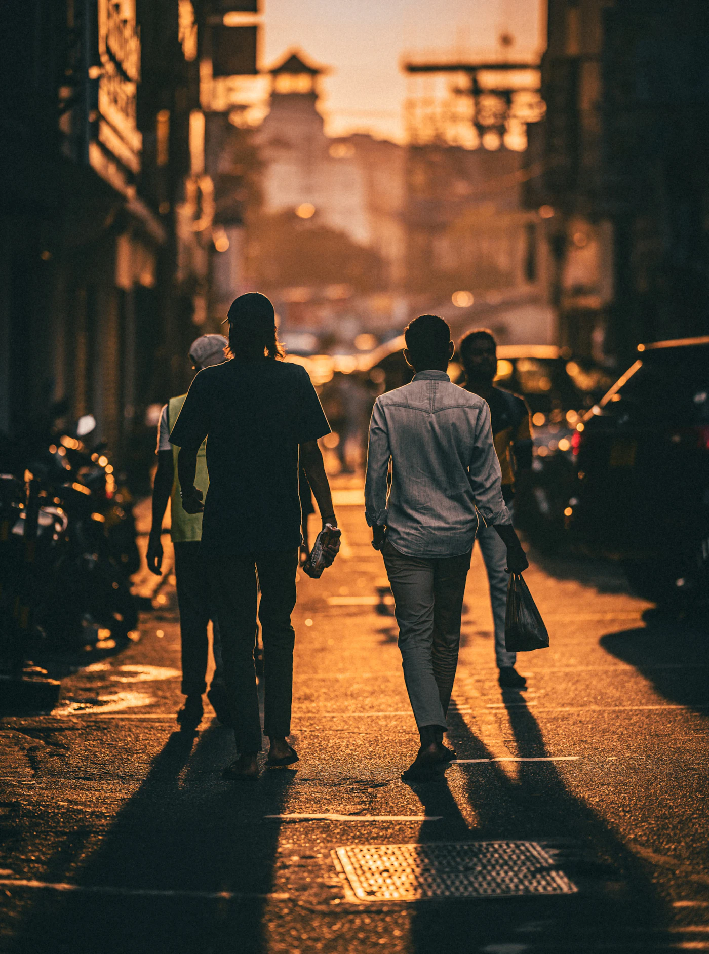 Two people walking a Colombo street in low evening light