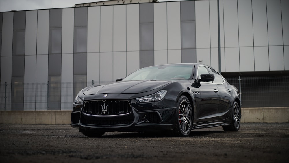 a black masera is parked in front of a building